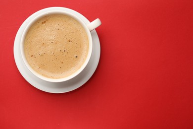 Fresh coffee in cup on red background, top view. Space for text