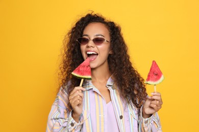 Photo of Beautiful young African American woman with pieces of watermelon on yellow background