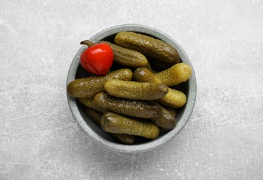 Photo of Bowl of pickled cucumbers and pepper on light grey table, top view