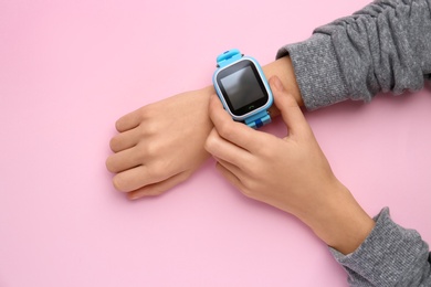 Boy with stylish smart watch on pink background, top view