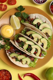 Photo of Flat lay composition with delicious tacos on yellow table