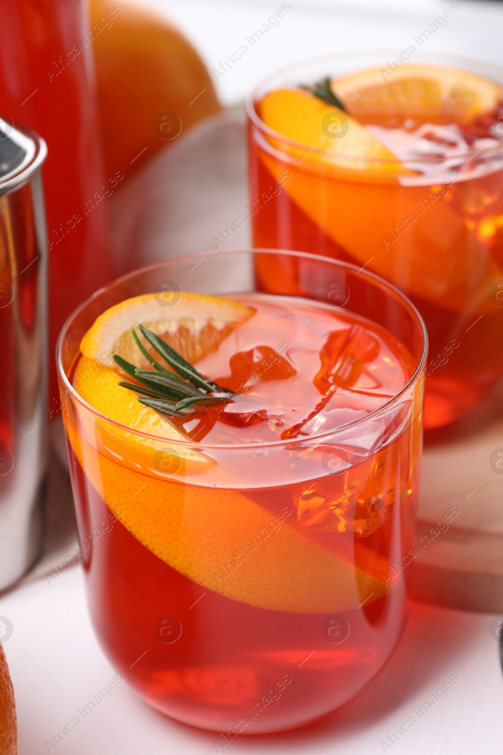 Photo of Aperol spritz cocktail, rosemary and orange slices on white table, closeup