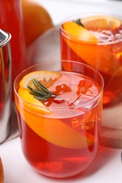 Photo of Aperol spritz cocktail, rosemary and orange slices on white table, closeup