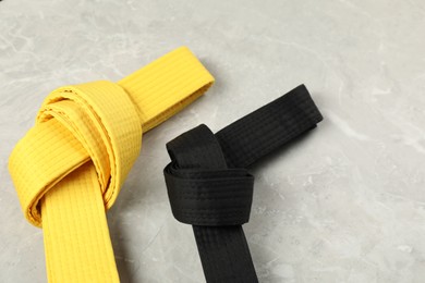 Black and yellow karate belts on gray marble background