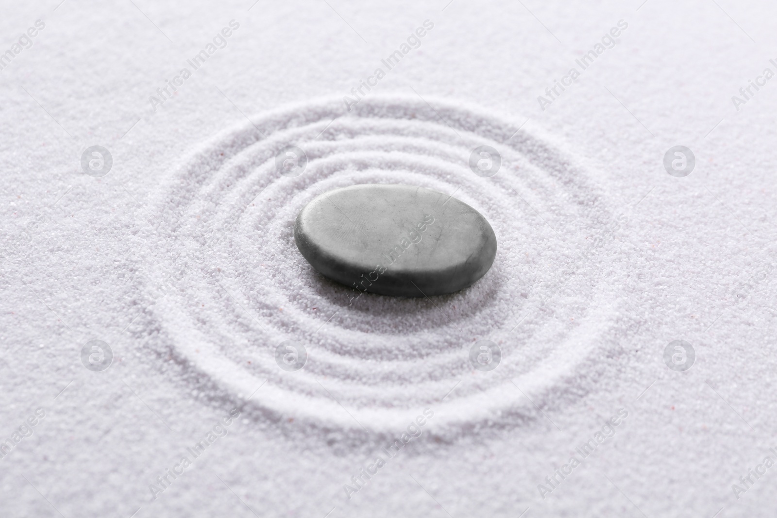 Photo of Zen garden stone on white sand with pattern