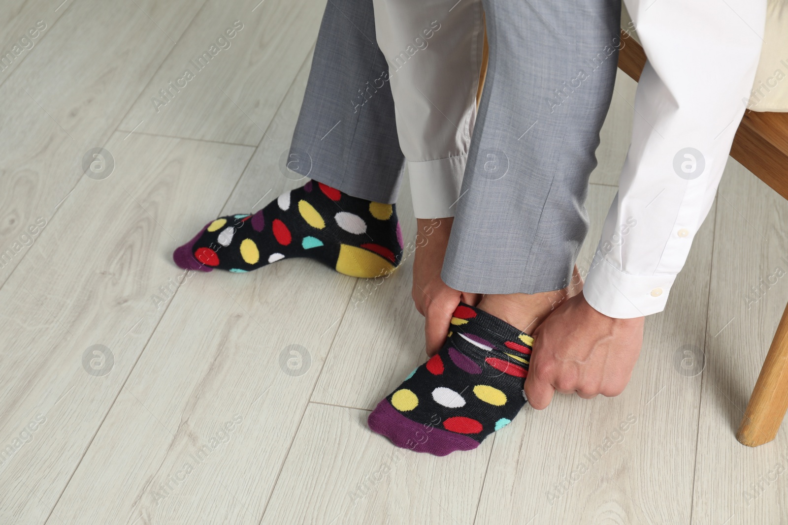 Photo of Man putting on colorful socks indoors, closeup