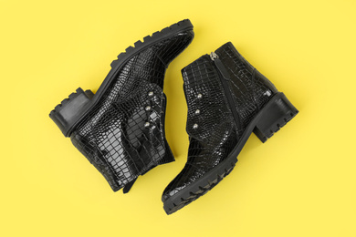 Photo of Pair of stylish ankle boots on yellow background, top view
