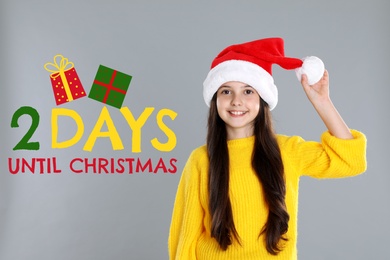 Christmas countdown. Happy little girl wearing Santa hat on light grey background near text