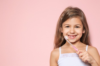 Photo of Portrait of little girl with toothbrush on color background. Space for text
