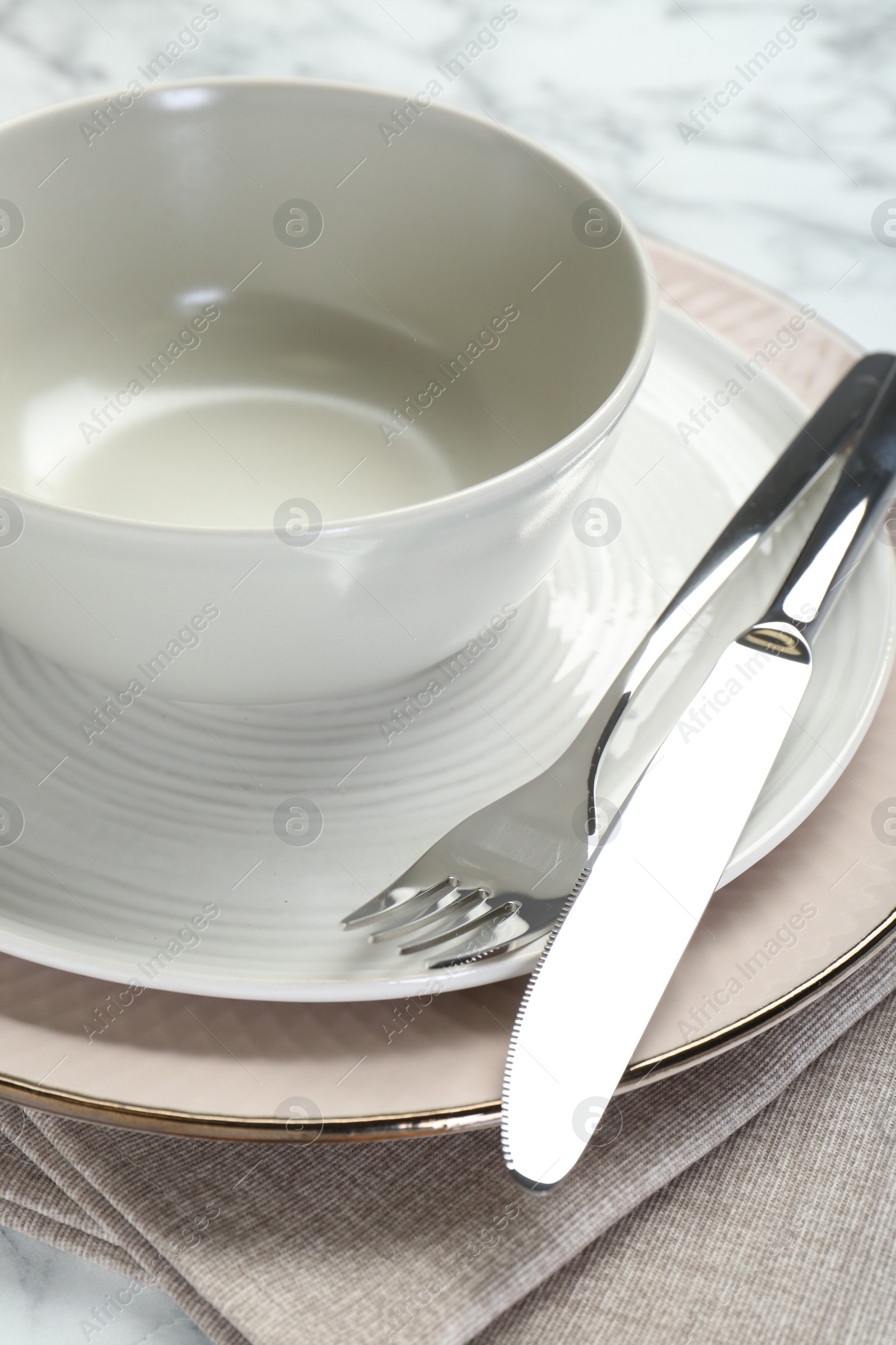 Photo of Clean plates, bowl, cutlery and napkin on table, closeup