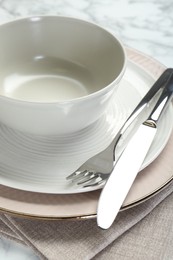 Clean plates, bowl, cutlery and napkin on table, closeup