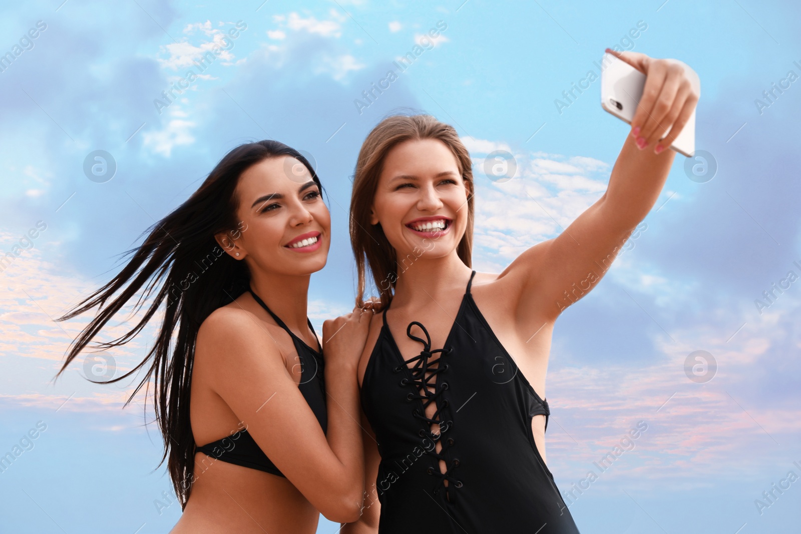 Photo of Young woman in bikini with girlfriend taking selfie outdoors. Lovely couple