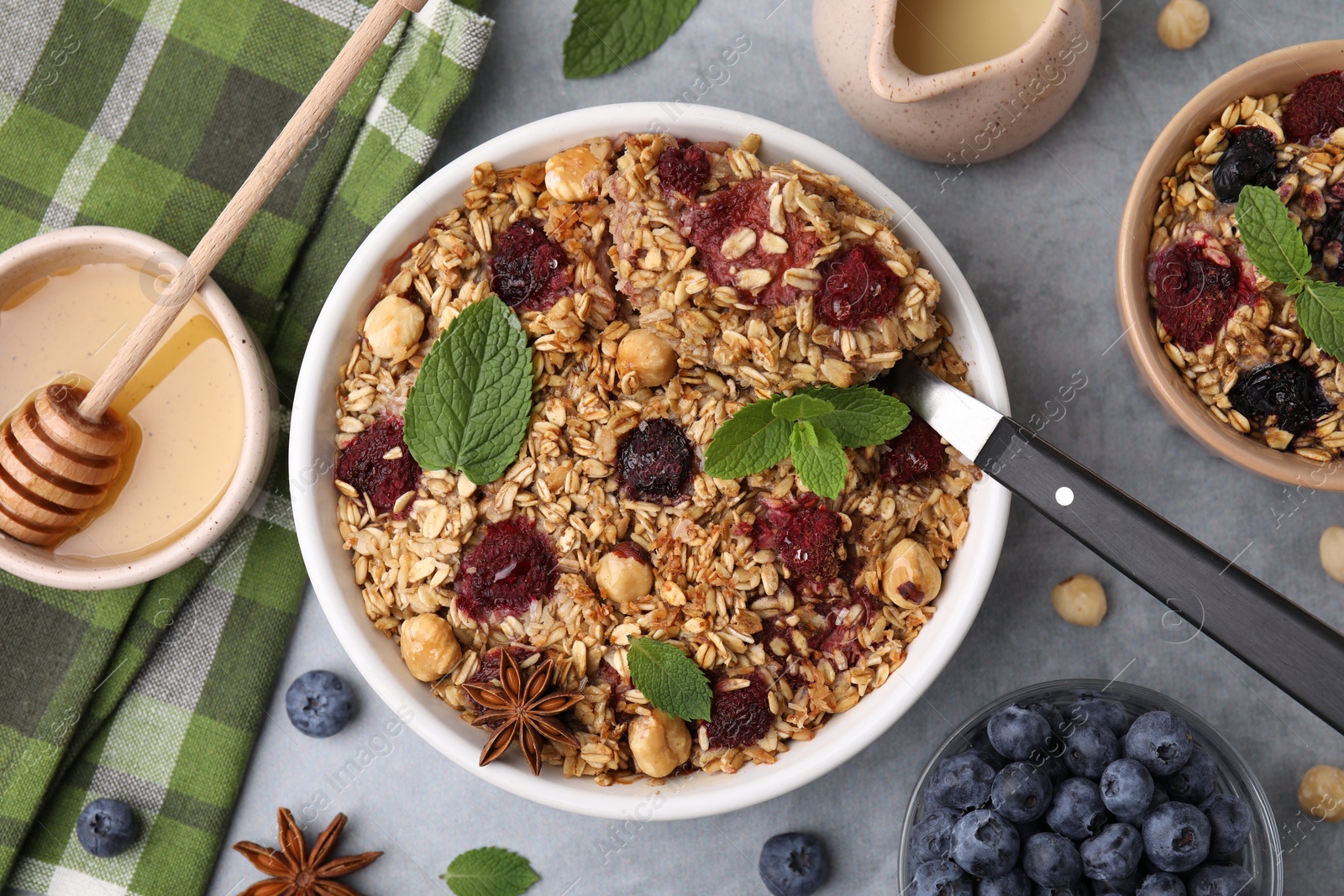 Photo of Tasty baked oatmeal with berries and nuts served on light grey table, flat lay