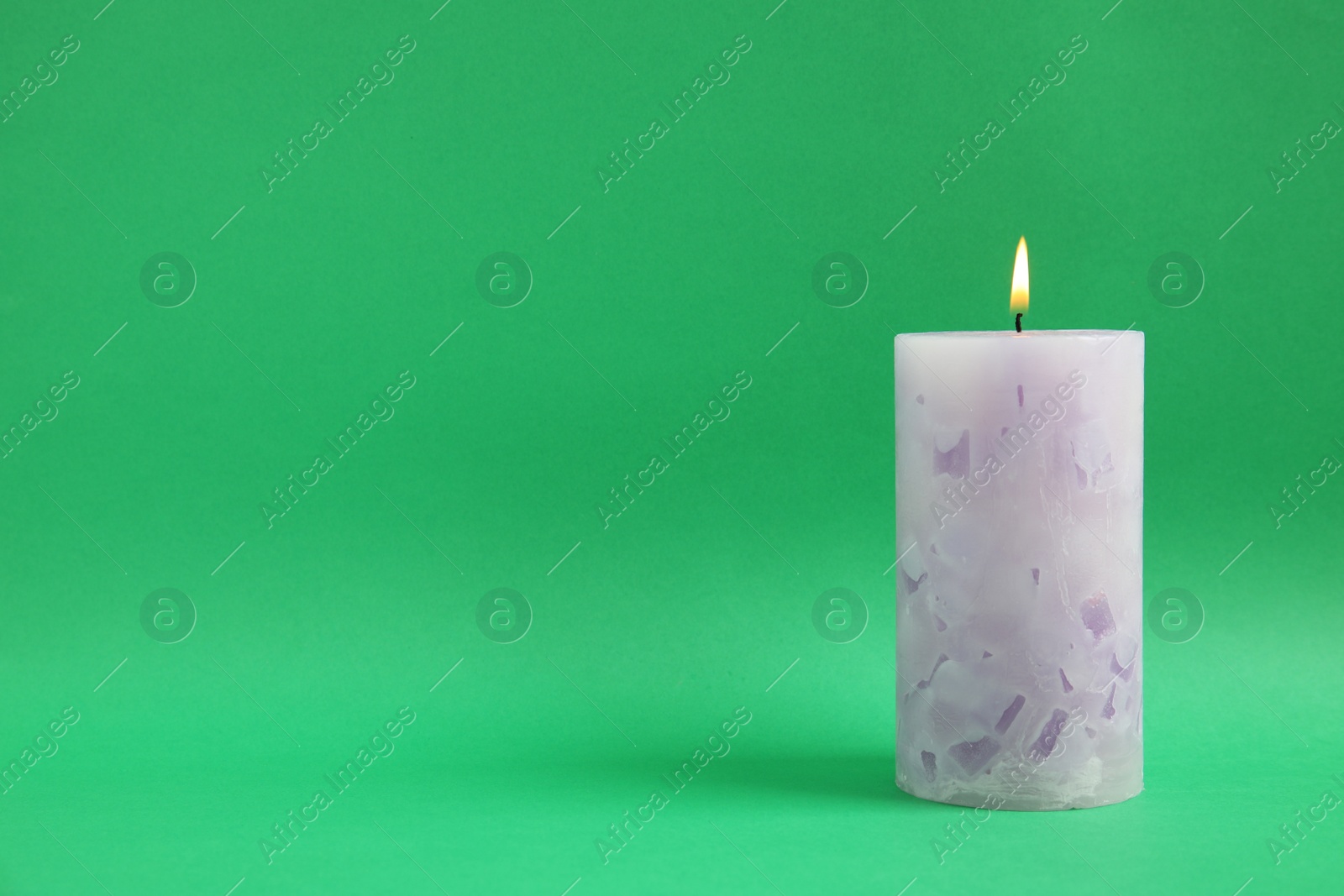 Photo of Alight wax candle on color background. Space for text