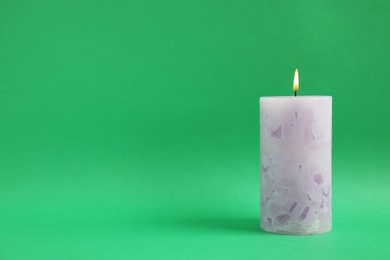 Alight wax candle on color background. Space for text