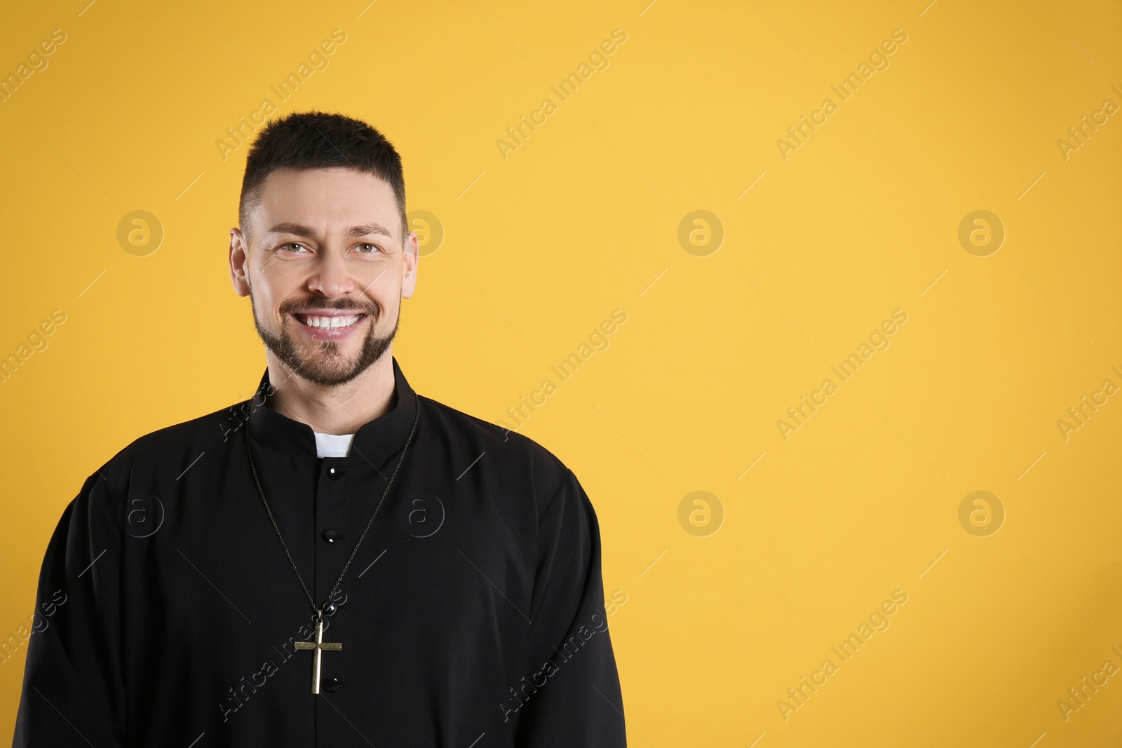 Photo of Priest wearing cassock with clerical collar on yellow background, space for text