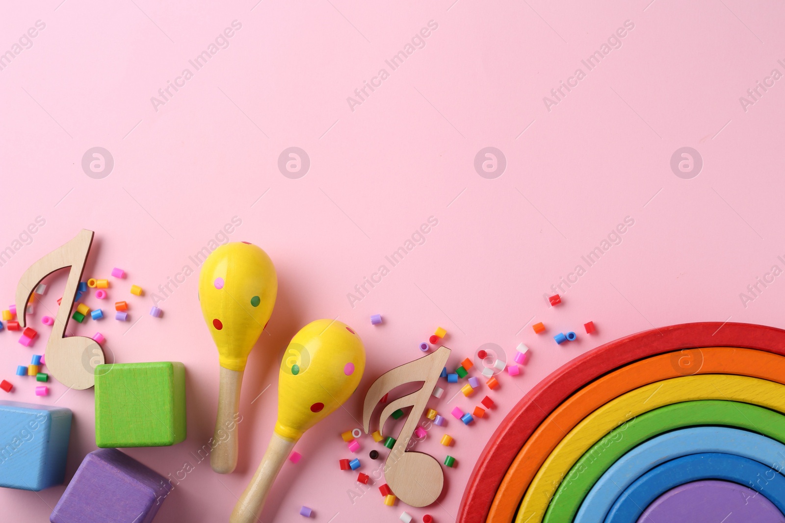 Photo of Baby song concept. Wooden notes, kids maracas and toys on pink background, flat lay. Space for text