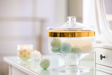 Photo of Jar with bath bombs and bath sponge on dressing table indoors