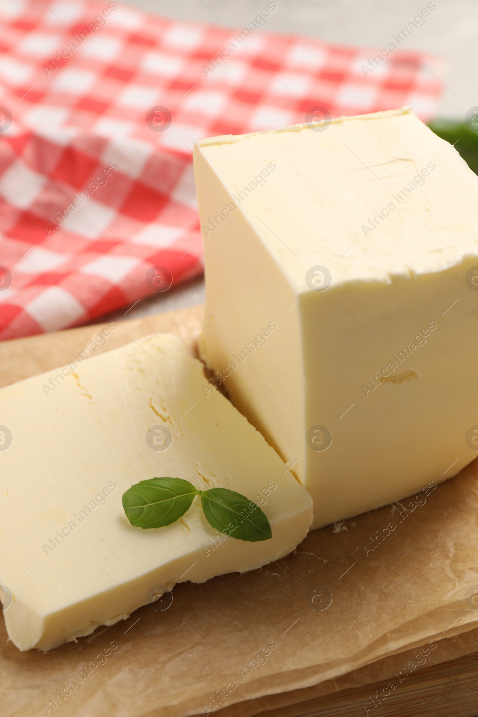 Photo of Block of tasty butter with basil on grey table, closeup