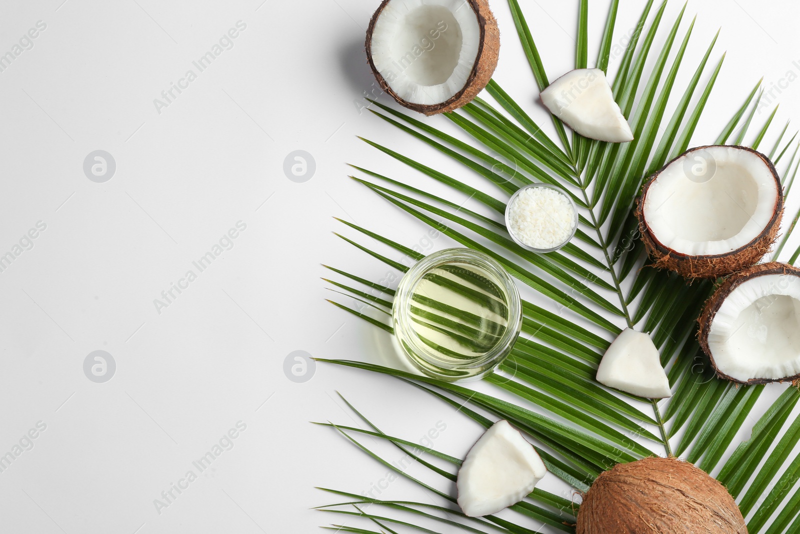 Photo of Jar of natural organic oil and coconuts on white background, top view