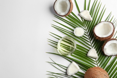 Jar of natural organic oil and coconuts on white background, top view