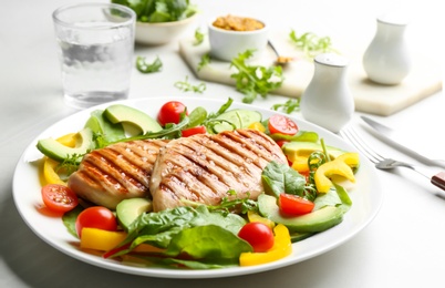 Tasty grilled chicken fillets with vegetables on light grey table, closeup