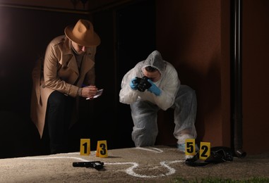 Photo of Investigator and criminologist working at crime scene outdoors in evening