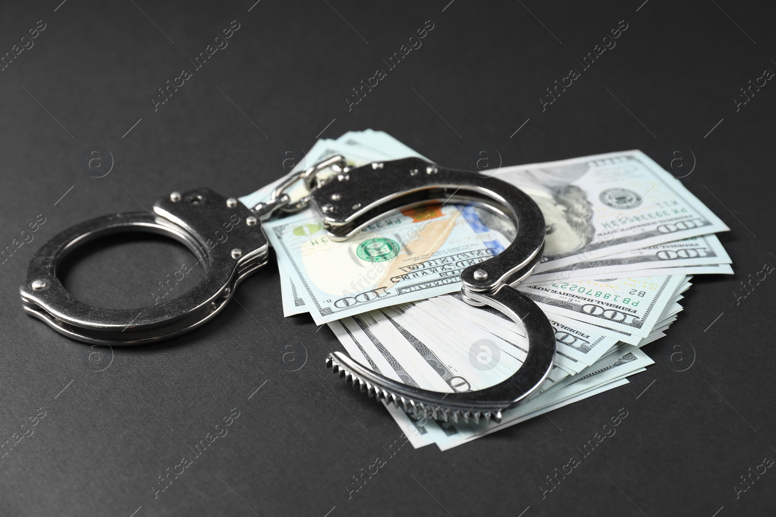 Photo of Dollars and metal handcuffs on grey table