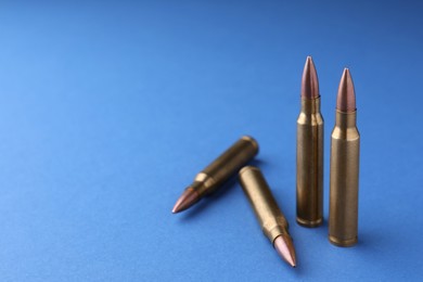 Photo of Bullets on blue background, closeup. Space for text