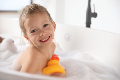 Photo of Cute little girl taking bubble bath at home