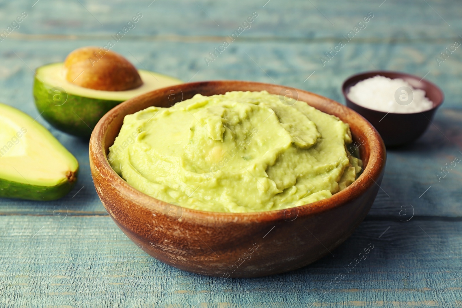 Photo of Bowl with guacamole made of ripe avocados on table