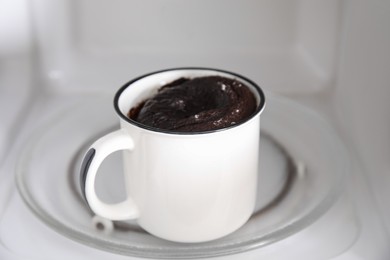 Tasty chocolate mug pie inside microwave. Cooking cake