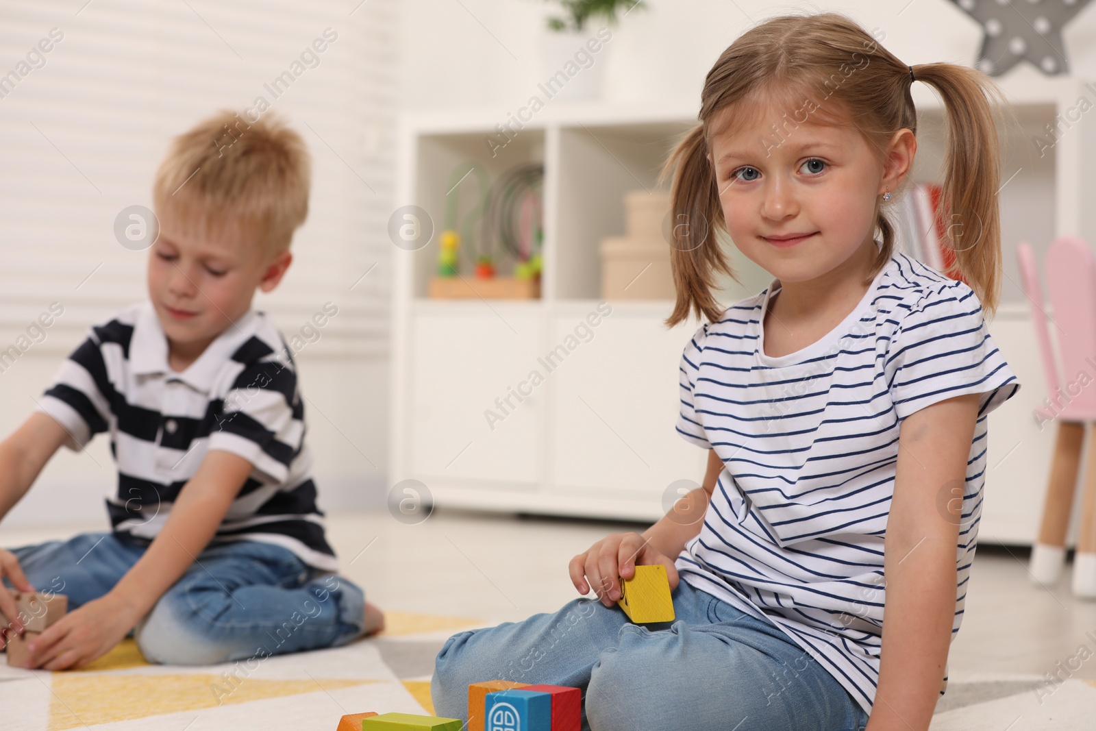 Photo of Little children playing with building blocks indoors. Wooden toys