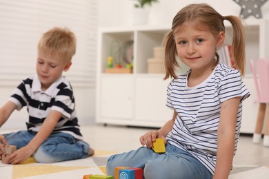 Photo of Little children playing with building blocks indoors. Wooden toys