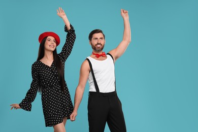 Happy couple dancing together on light blue background, space for text