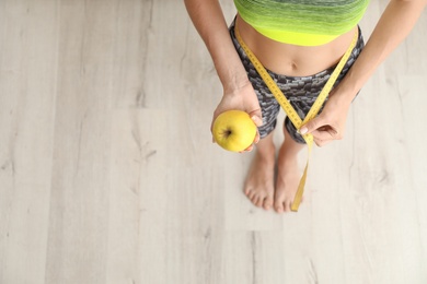 Photo of Woman with fresh apple and measuring tape, top view. Healthy diet