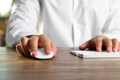 Photo of Man using computer mouse and keyboard at table, closeup