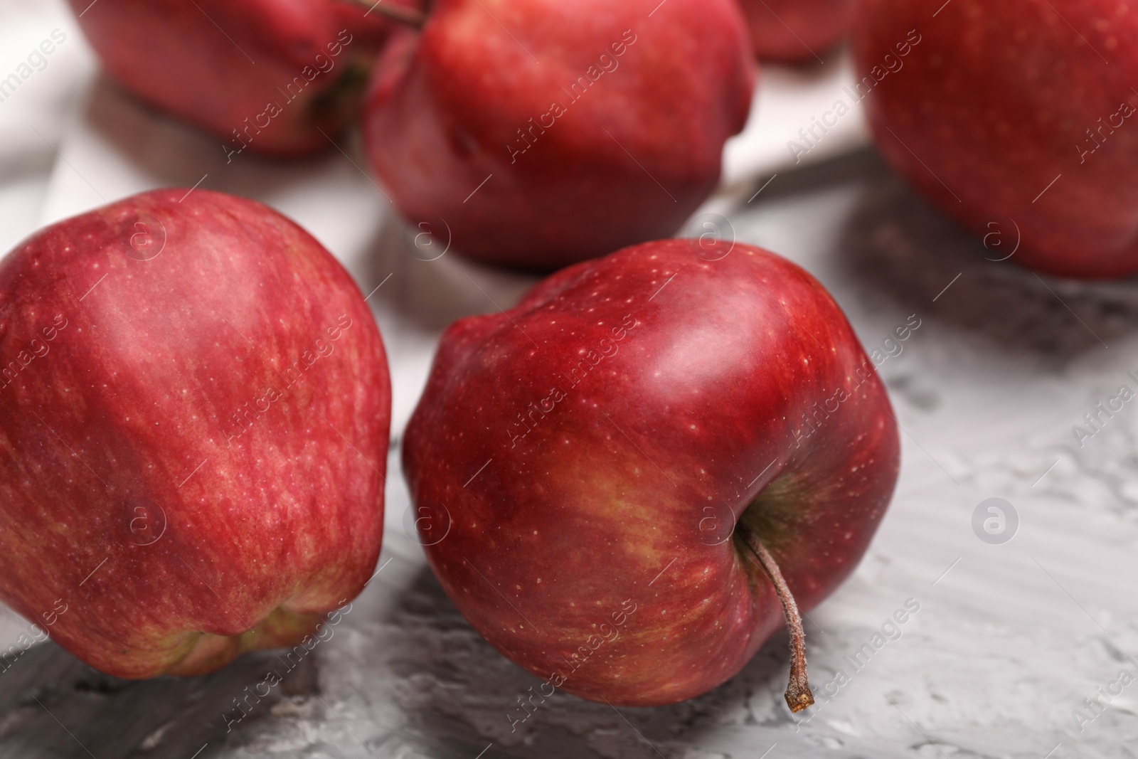 Photo of Fresh red apples on grey textured table, closeup