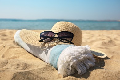 Photo of Straw hat, towel and sunglasses on sandy beach