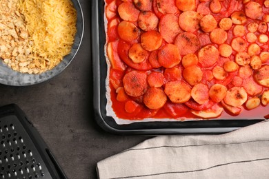 Photo of Tasty parsnips with sauce and ingredients on dark grey textured table, flat lay