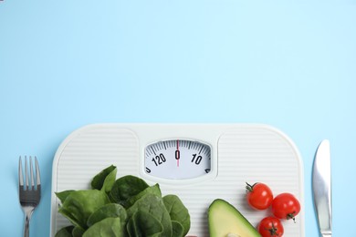 Photo of Scales, healthy food and cutlery on light blue background, flat lay. Space for text