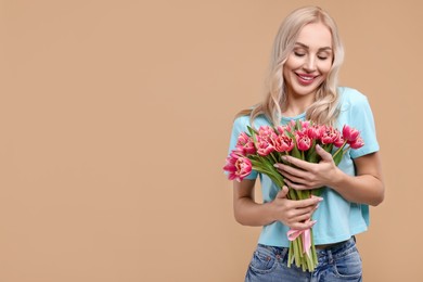 Happy young woman with beautiful bouquet on beige background. Space for text