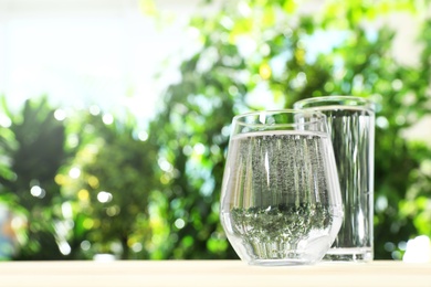 Glasses of water on table against blurred background, space for text. Refreshing drink