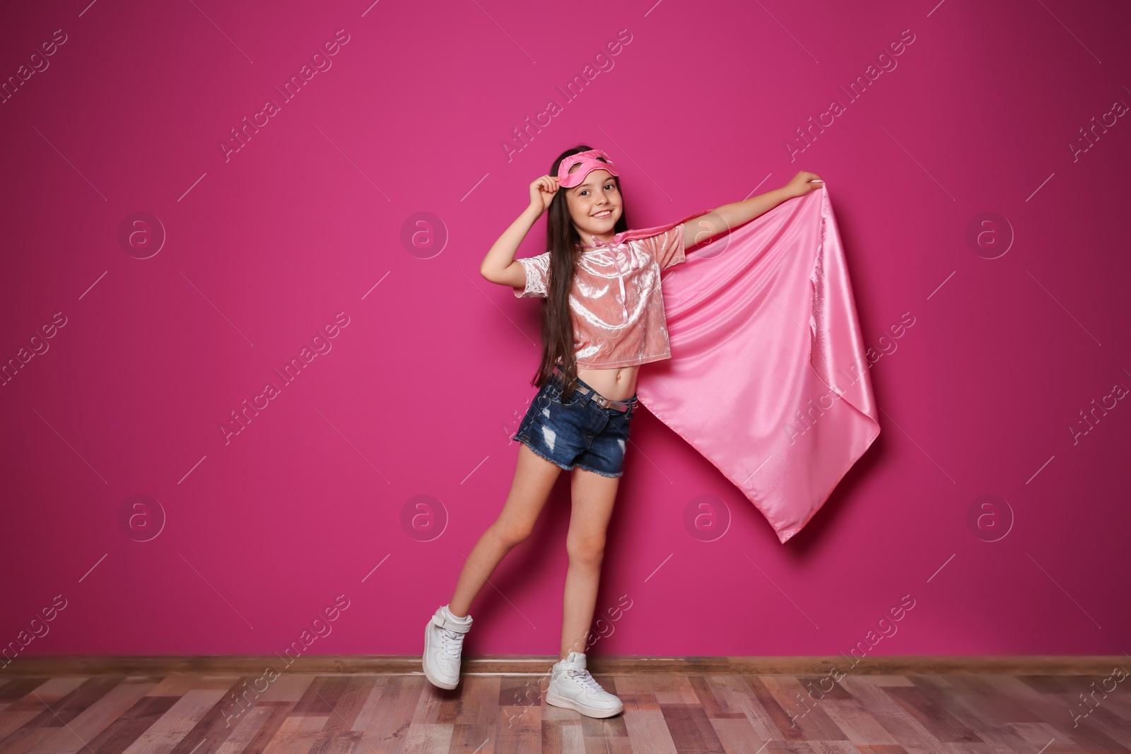 Photo of Adorable little child playing superhero indoors