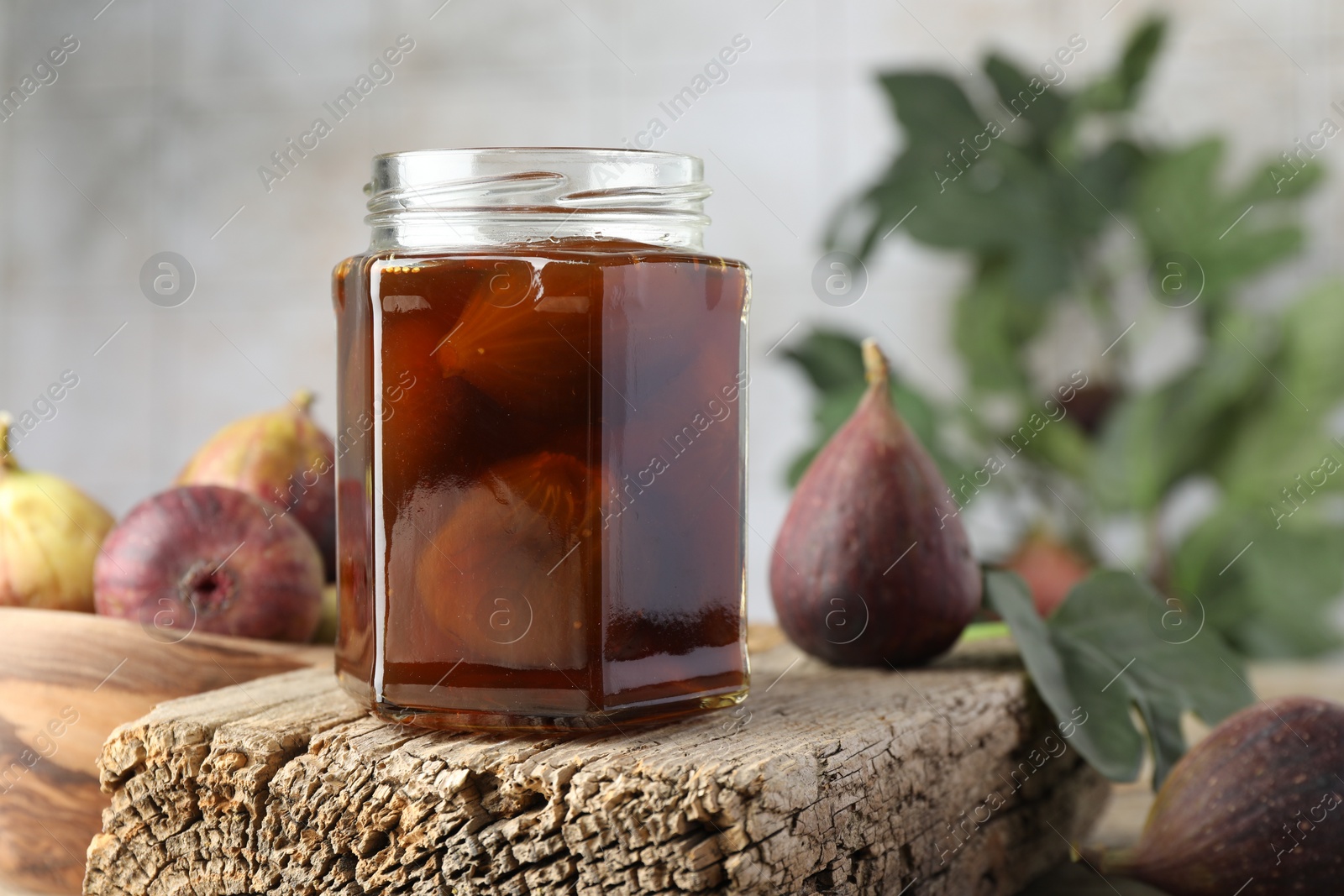 Photo of Jar of tasty sweet jam and fresh figs on wooden board