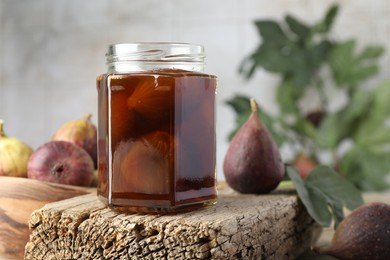 Jar of tasty sweet jam and fresh figs on wooden board