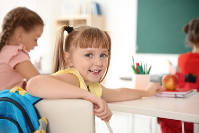 Photo of Cute little child sitting at desk in classroom. Elementary school