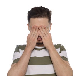 Embarrassed man covering eyes with hands on white background