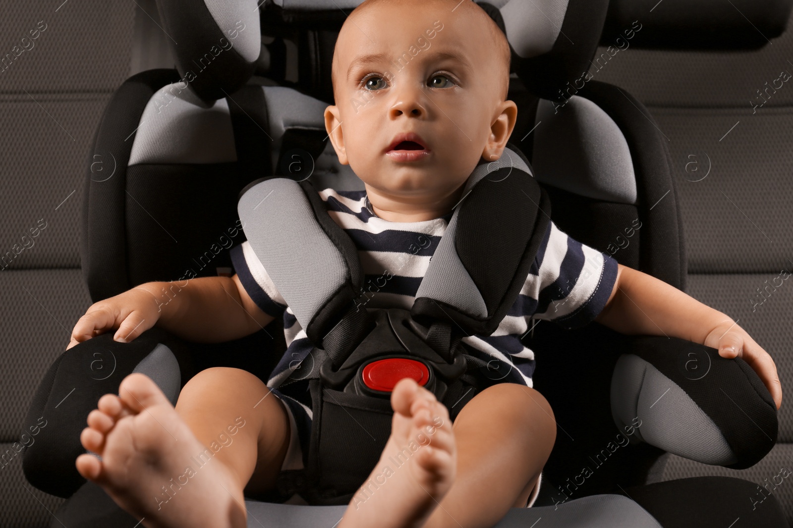 Photo of Cute little boy sitting in child safety seat inside car