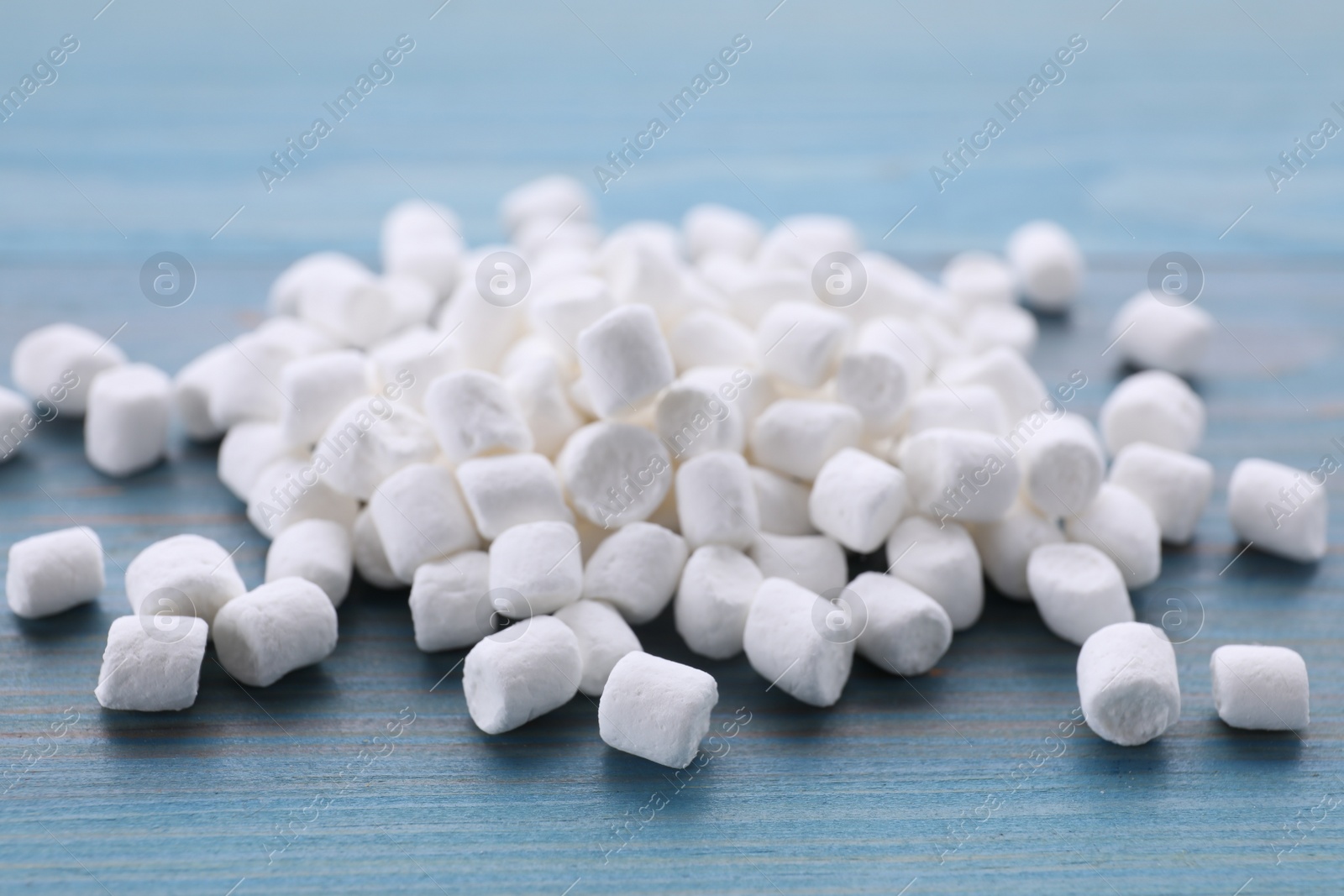 Photo of Delicious marshmallows on light blue wooden table, closeup